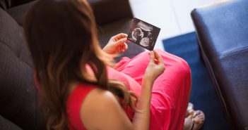 Schwangere mit Ultraschallbild in den Händen.